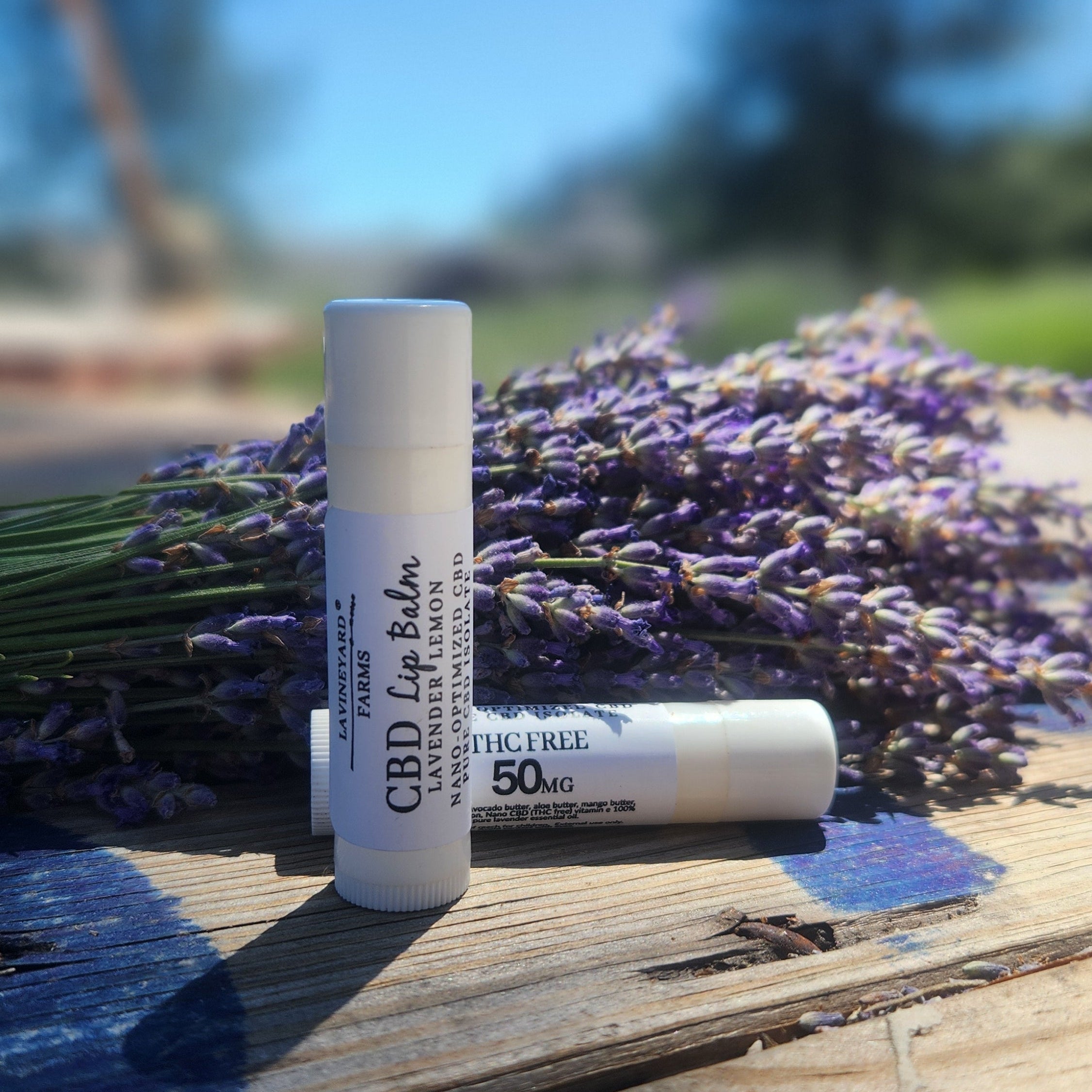 CPD lip balm standing on a table with lavender flowers behind