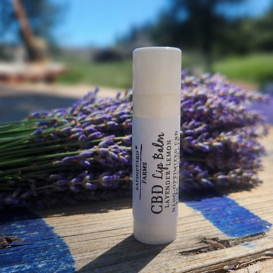 CPD lip balm standing on a table with lavender flowers behind